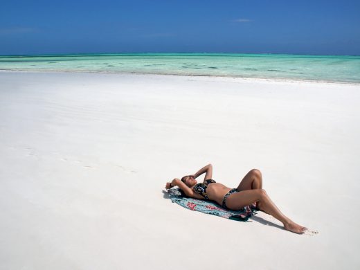 Young,Girl,Lying,And,Sunbathing,On,White,Sand,Beach.,Paje
