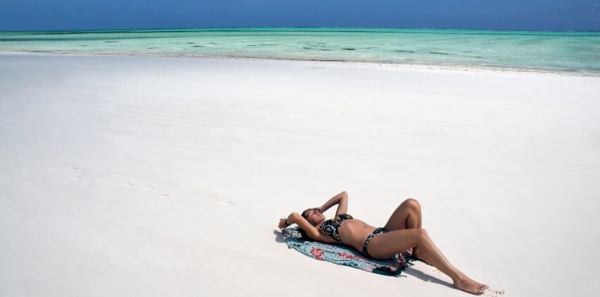 Young,Girl,Lying,And,Sunbathing,On,White,Sand,Beach.,Paje