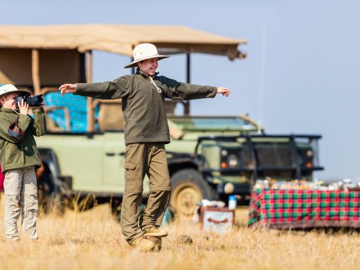 Guests enjoying a private bush sundowner experience beside a safari vehicle in Tanzania.
