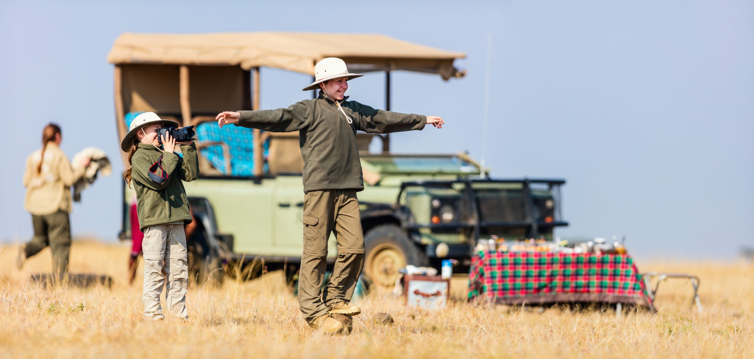 Guests enjoying a private bush sundowner experience beside a safari vehicle in Tanzania.